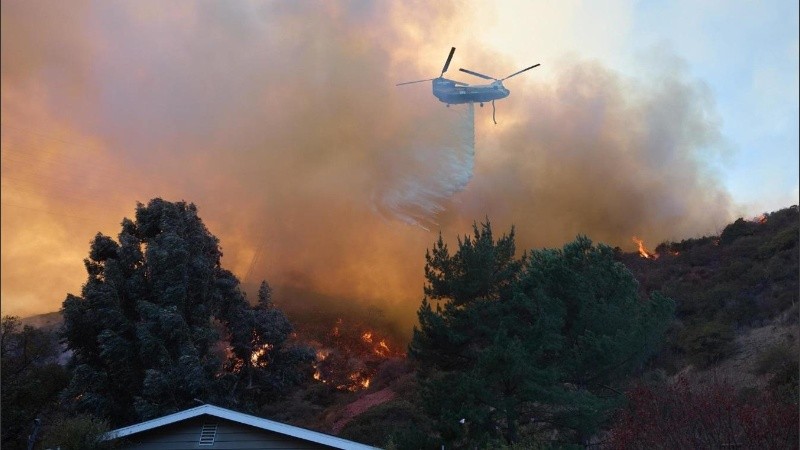 Un helicóptero arroja agua en medio del incendio de Palisades, el foco más activo de Los Ángeles.