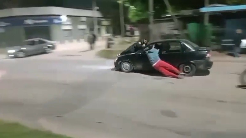 La secuencia muestra cómo el vehículo negro acelera mientras dos manifestantes intentan frenarlo.