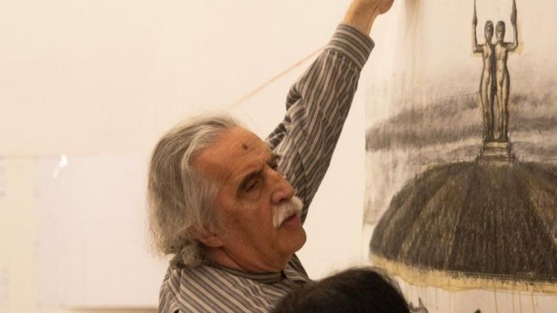 Daniel Santoro mientras colgaba la obra, en la que se ve un dibujo de Las Mellizas sobre la cúpula del Palacio Minetti.