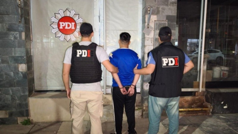Oficiales de la PDI haciendo posar al sospechoso en su llegada a Santa Fe.