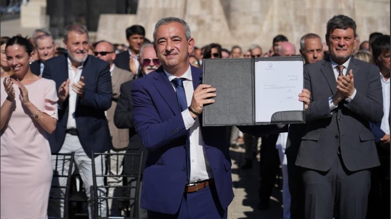El intendente muestra orgulloso la ordenanza promulgada al pie del Monumento a la Bandera.