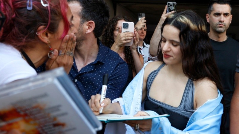 Rosalía en su última visita al país, firma autógrafos con una bandera argentina.