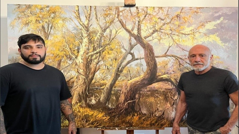 Los artistas Mario Domínguez Teixeira y su hijo Rodrigo Domínguez, posando con una obra del pintor del río y antedecesor de ambos.