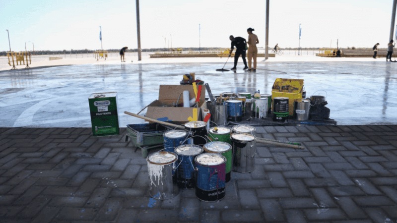 Los artistas trabajan sobre el suelo en el laqueado del mural 