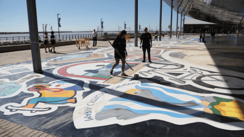 Los artistas trabajan sobre el suelo en el laqueado del mural 
