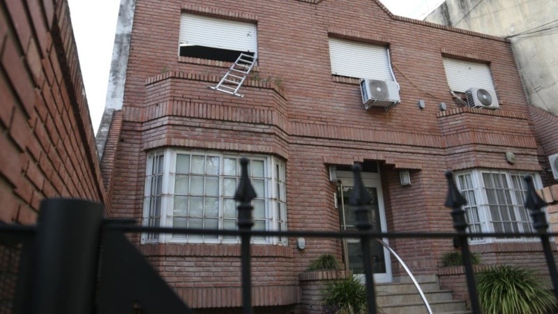 El frente de la casa donde el hombre se encontraba trabajando y la imagen de la escalera de aluminio suspendida en la ventana.
