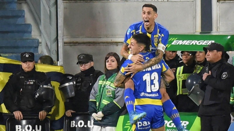 El Gato Ávila celebra con Di María colgado, tras su gol (Fotobaires).