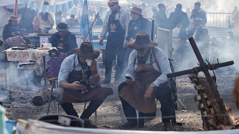 Un 20 de junio no puede faltar el asado, pero nadie suelta el celular (Alan Monzón/Rosario3).
