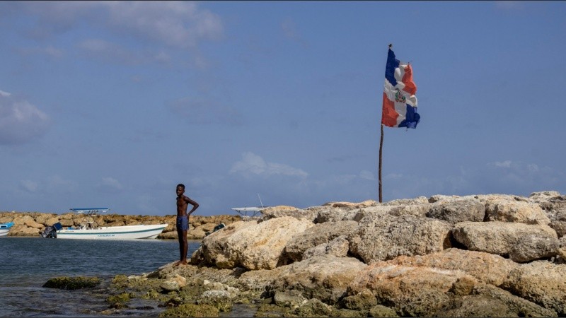 Un niño local observa desde la escollera de playa La Caleta la llegada de una de las lanchas con turistas.