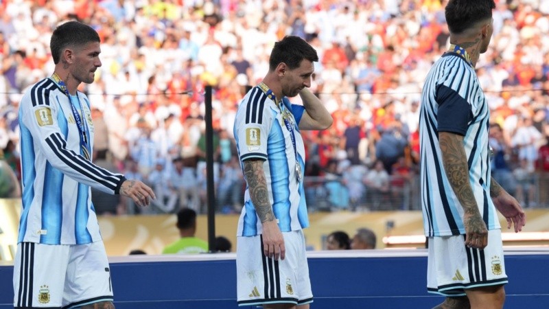Messi, entre Enzo Fernández y De Paul luego de ir a buscar la medalla del subcampeonato del mundo. (EFE)